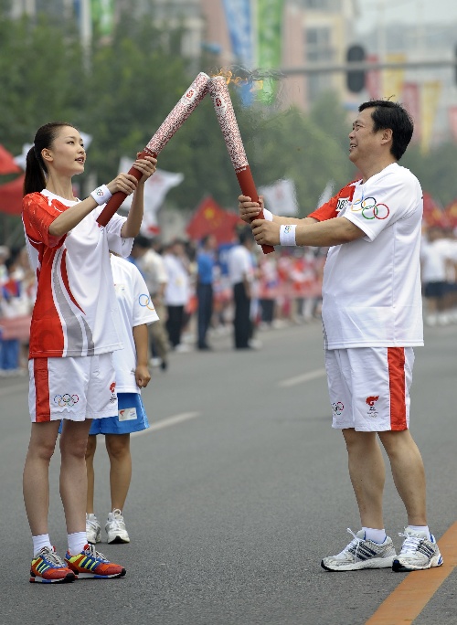 8月8日,火炬手张春江(右)与下一棒火炬手杜鹃交接.
